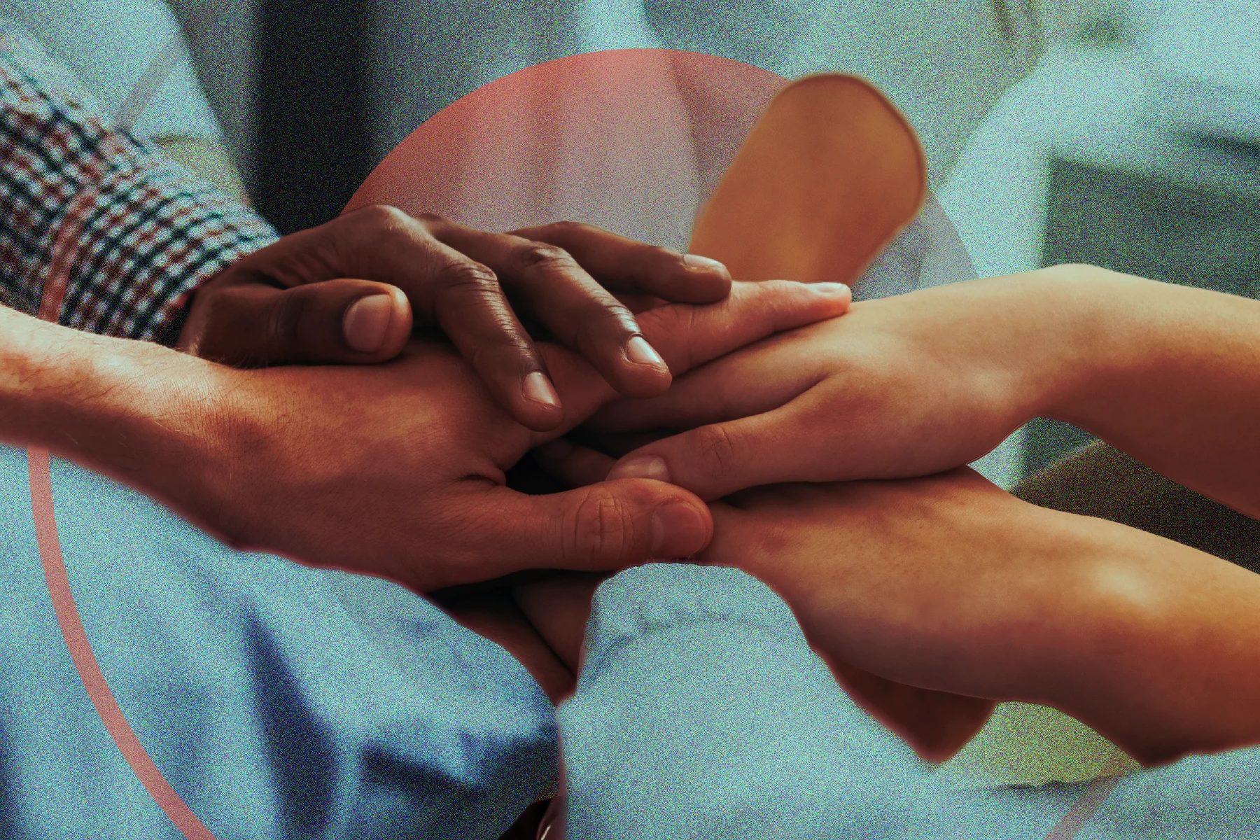 A close-up of several people’s hands stacked together, with the sleeves of their dress shirts visible and a soft red circle overlaying the image.