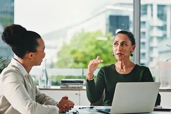 Two colleagues giving and receiving feedback during a one-on-one workplace conversation.