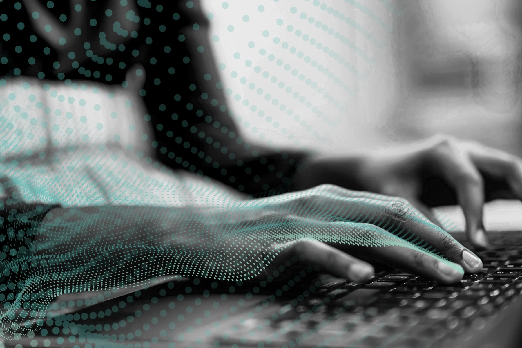 A black and white close-up of someone typing on a keyboard, with a digital overlay of turquoise dots.