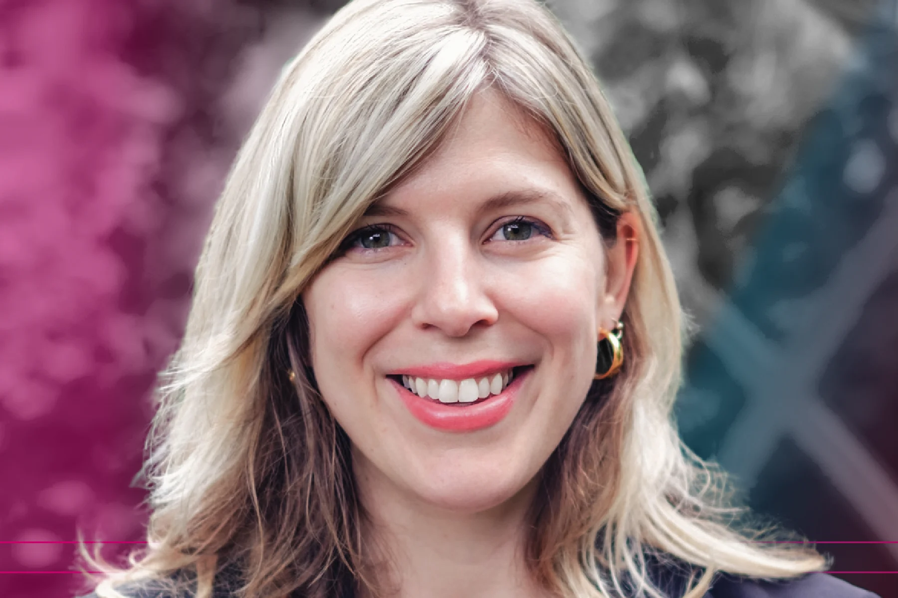 Close-up portrait of a smiling woman with shoulder-length blonde hair, wearing a dark blazer and gold jewelry, against a blurred background with magenta and blue overlays.
