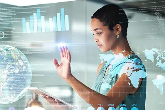 Person using a transparent touchscreen interface displaying global data, graphs, and digital charts.