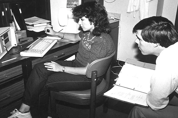 Two students, one male, one female, working at a computer, circa 1980.