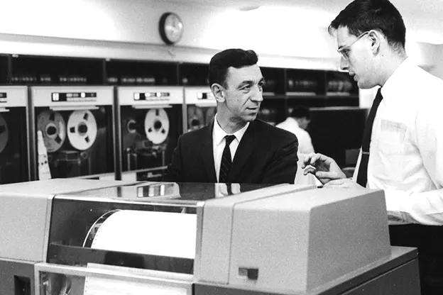 Two men talking over a an IBM 1401 computer, circa 1964.