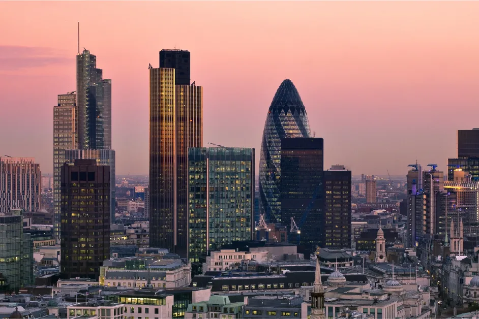 London skyline at sunset featuring the Gherkin and surrounding modern skyscrapers.