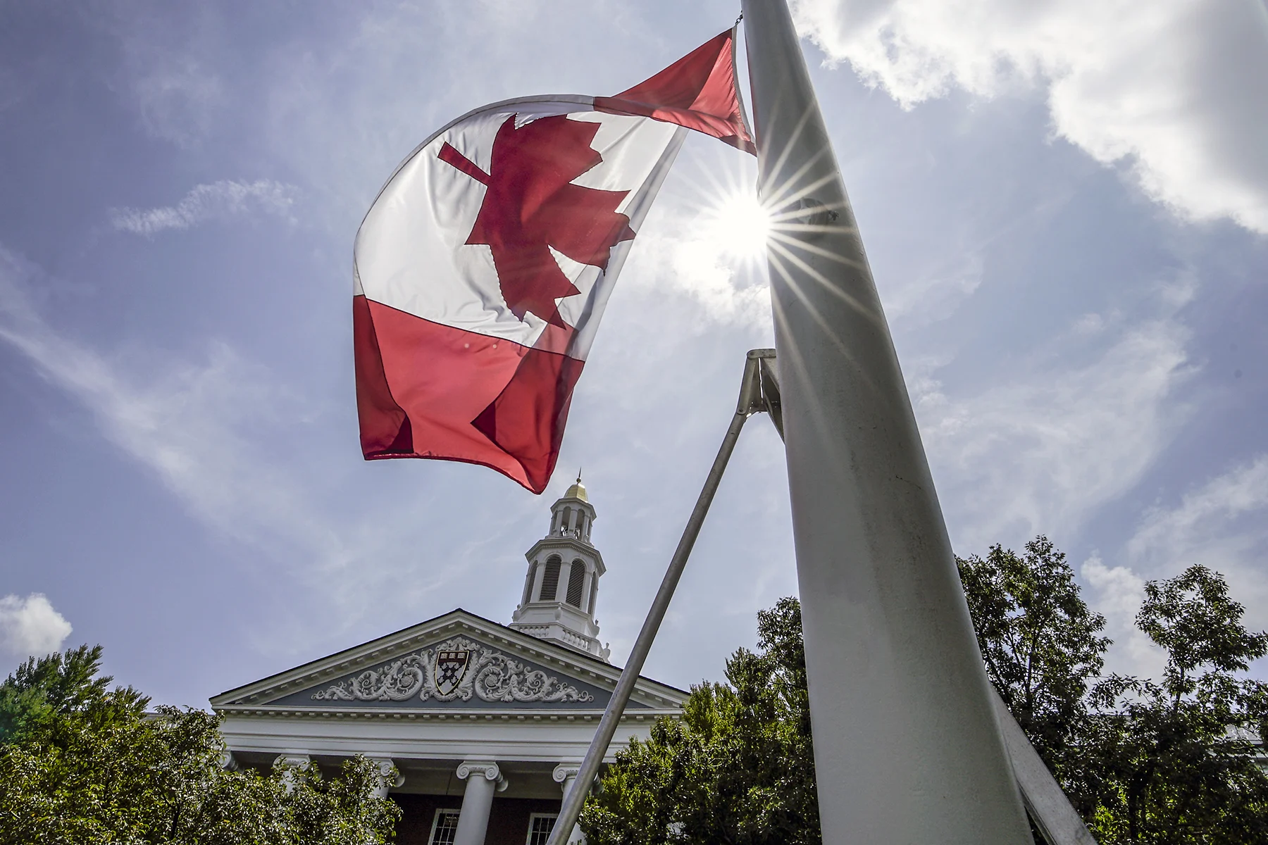 A Canadian flag flying in front of Baker Library.