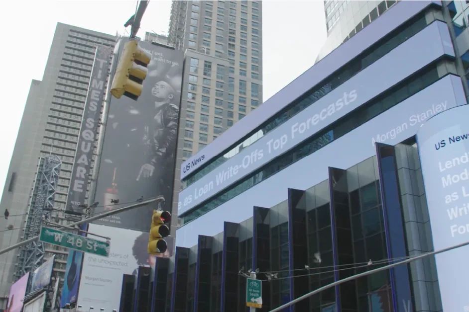 Times Square skyscrapers with digital news ticker showing financial headlines.