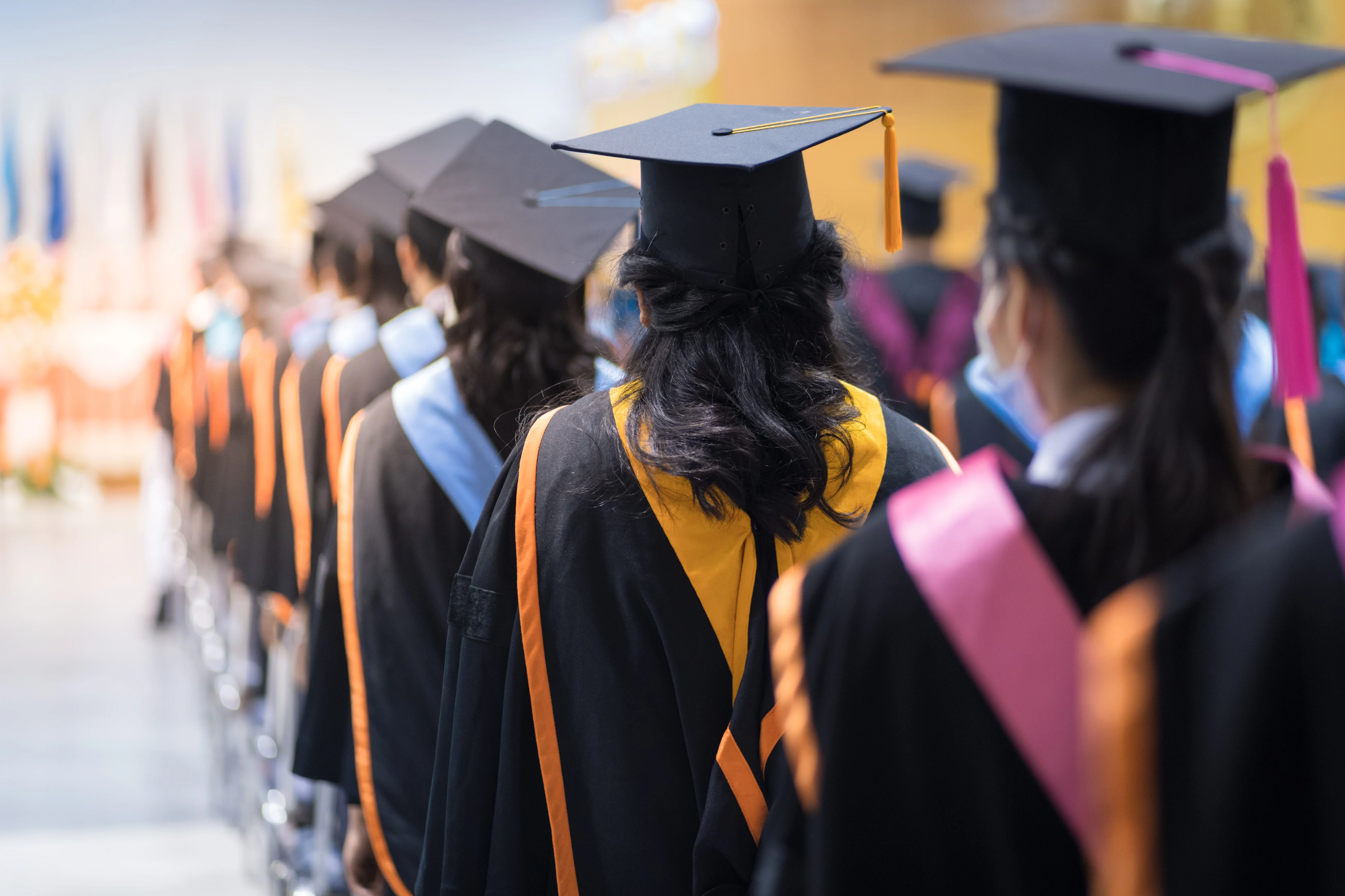 women standing in graduation robes waiting to graduate
