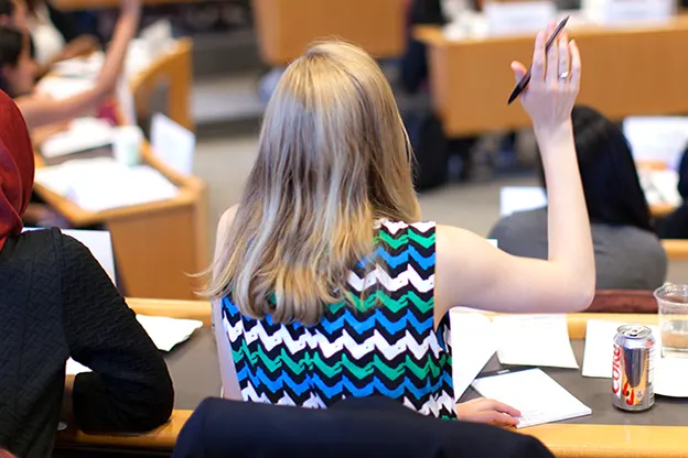 Woman raising hand in MBA classroom at Peek weekend