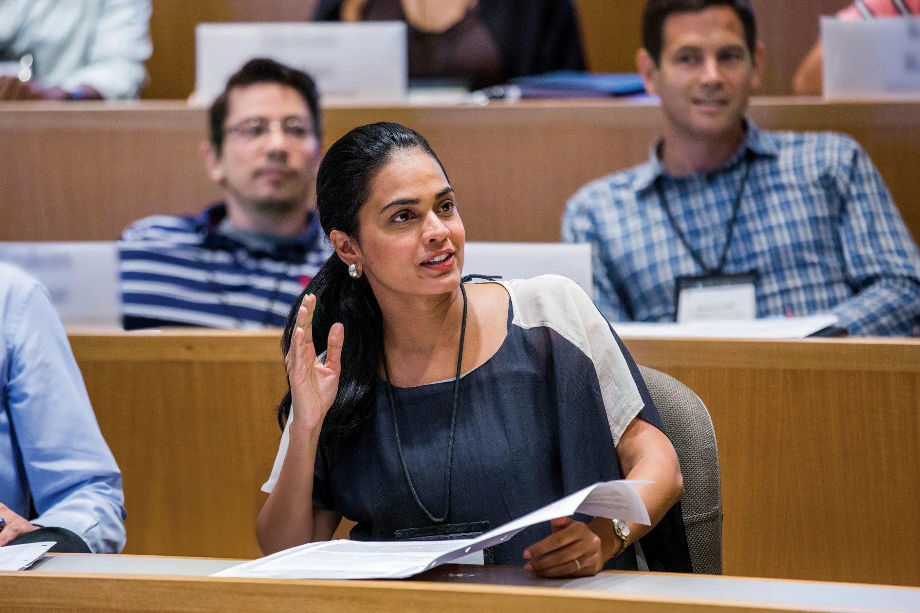Female executive raises hand to participate in classroom lecture discussion