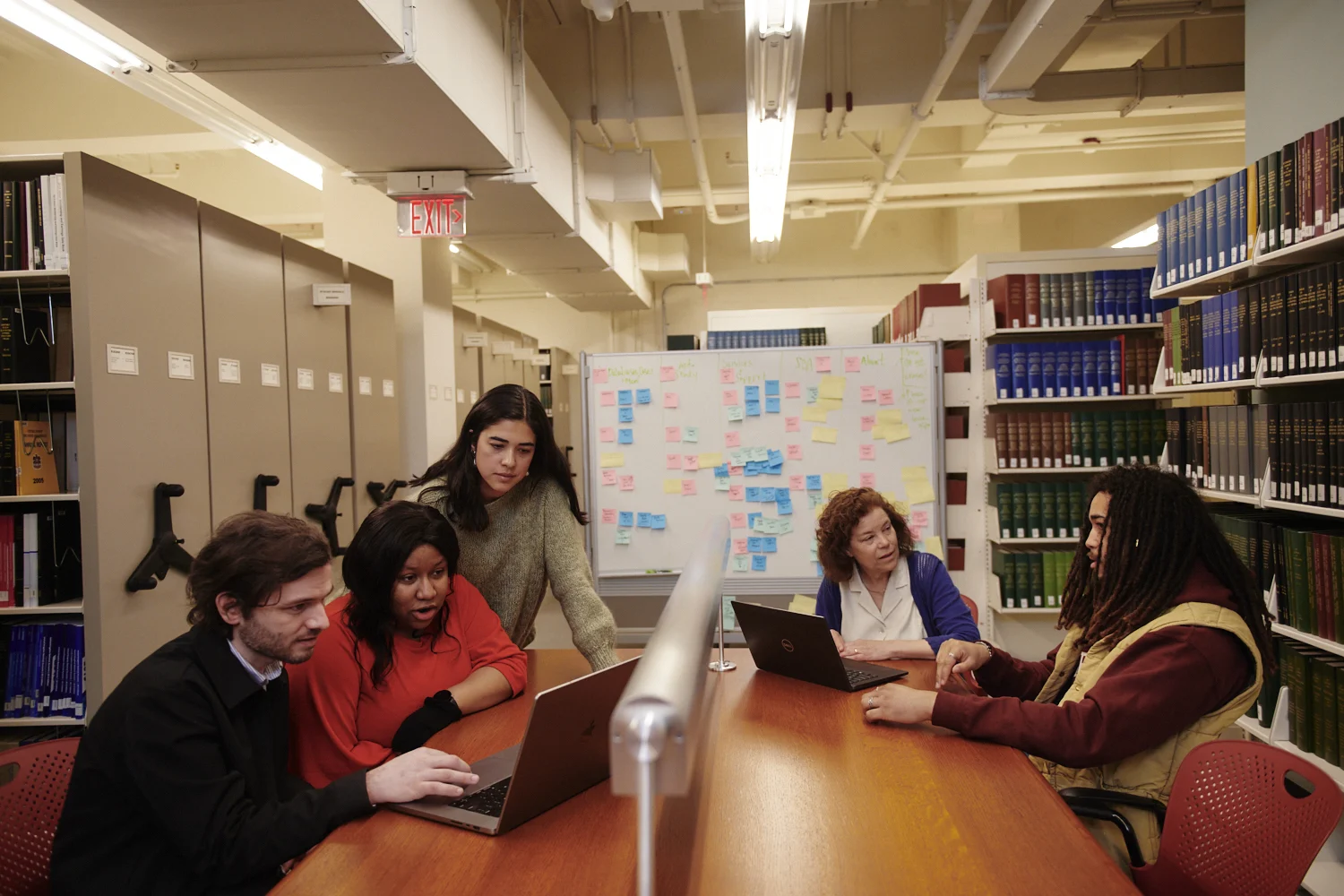 Librarian and students interacting in Baker Library stacks