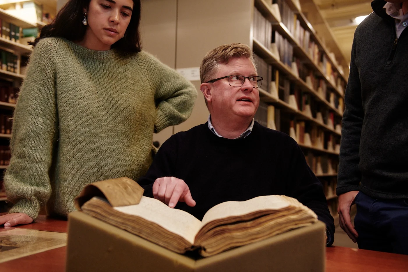 Man pointing to book bound in parchment