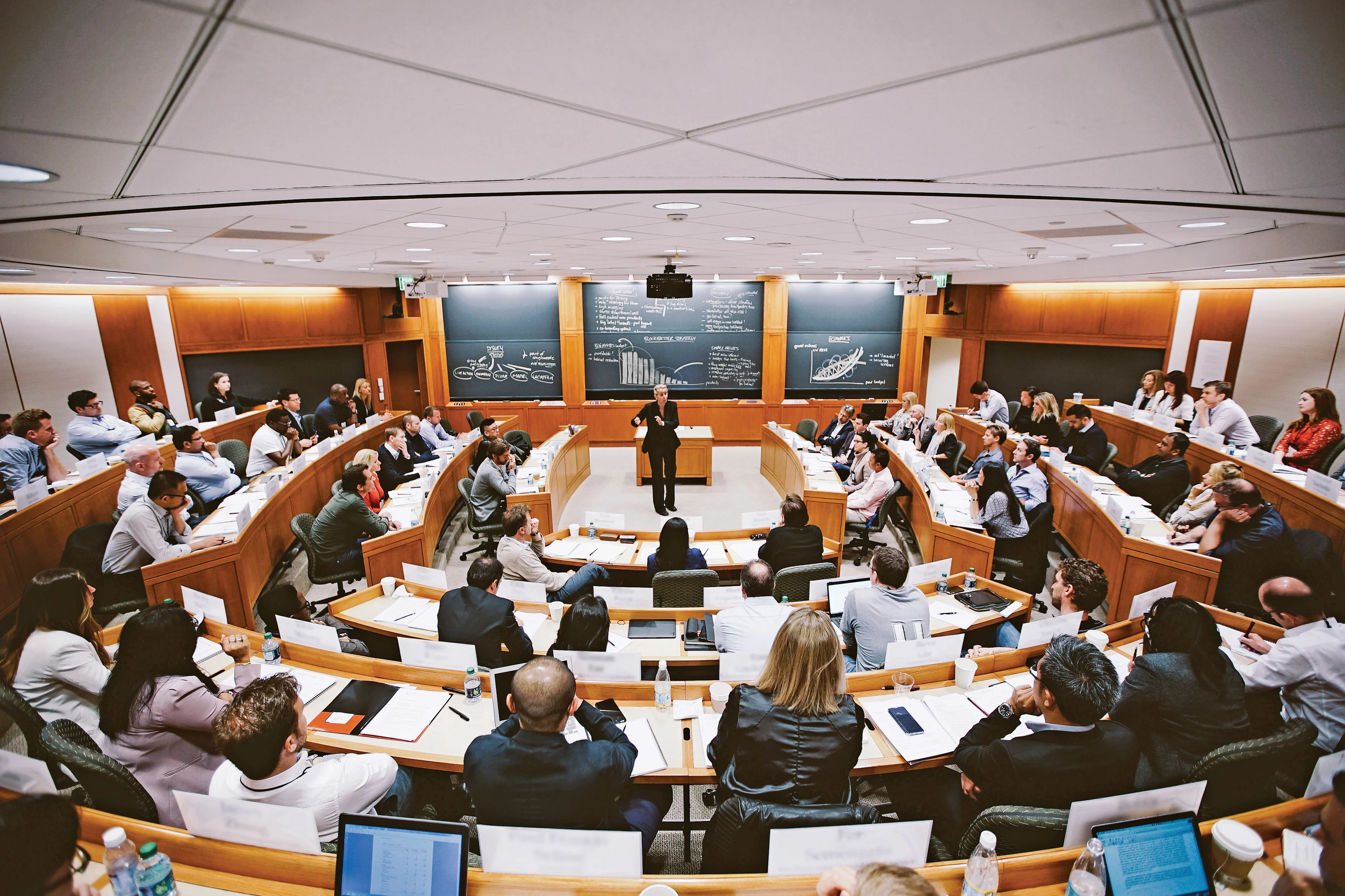 View from the back of a full HBS classroom with a professor in the center