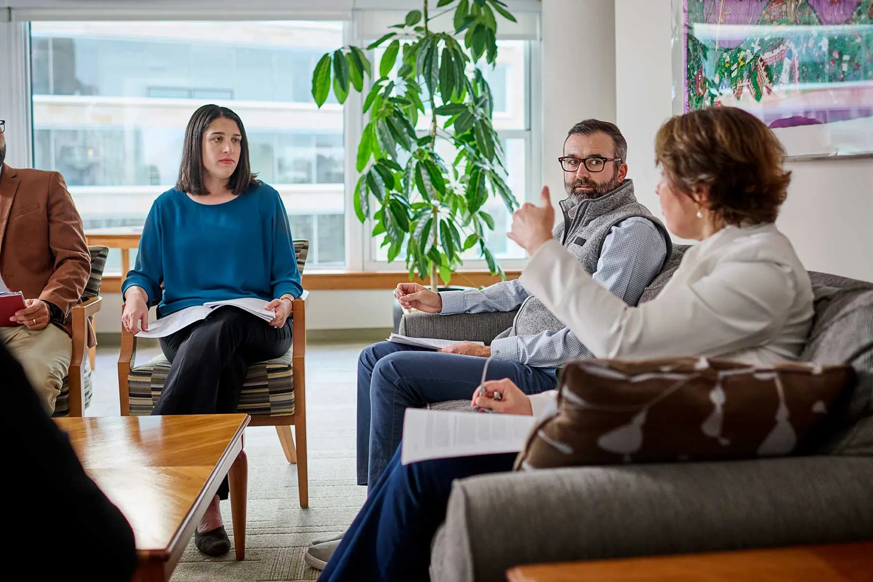 A group of Executives engaged in a discussion in a modern office setting, holding documents and taking notes