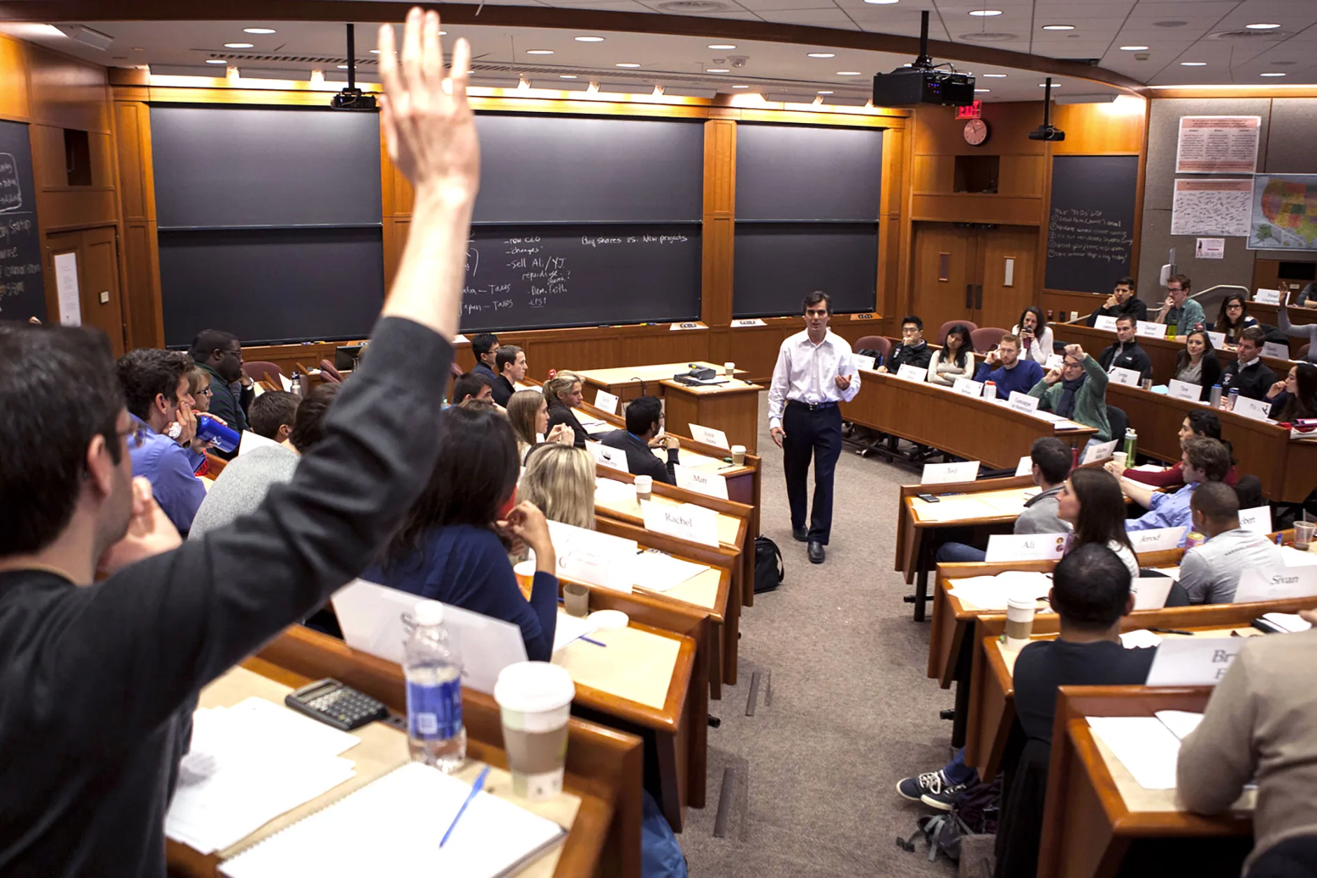 MBA students raising hands in classroom during a case discussion