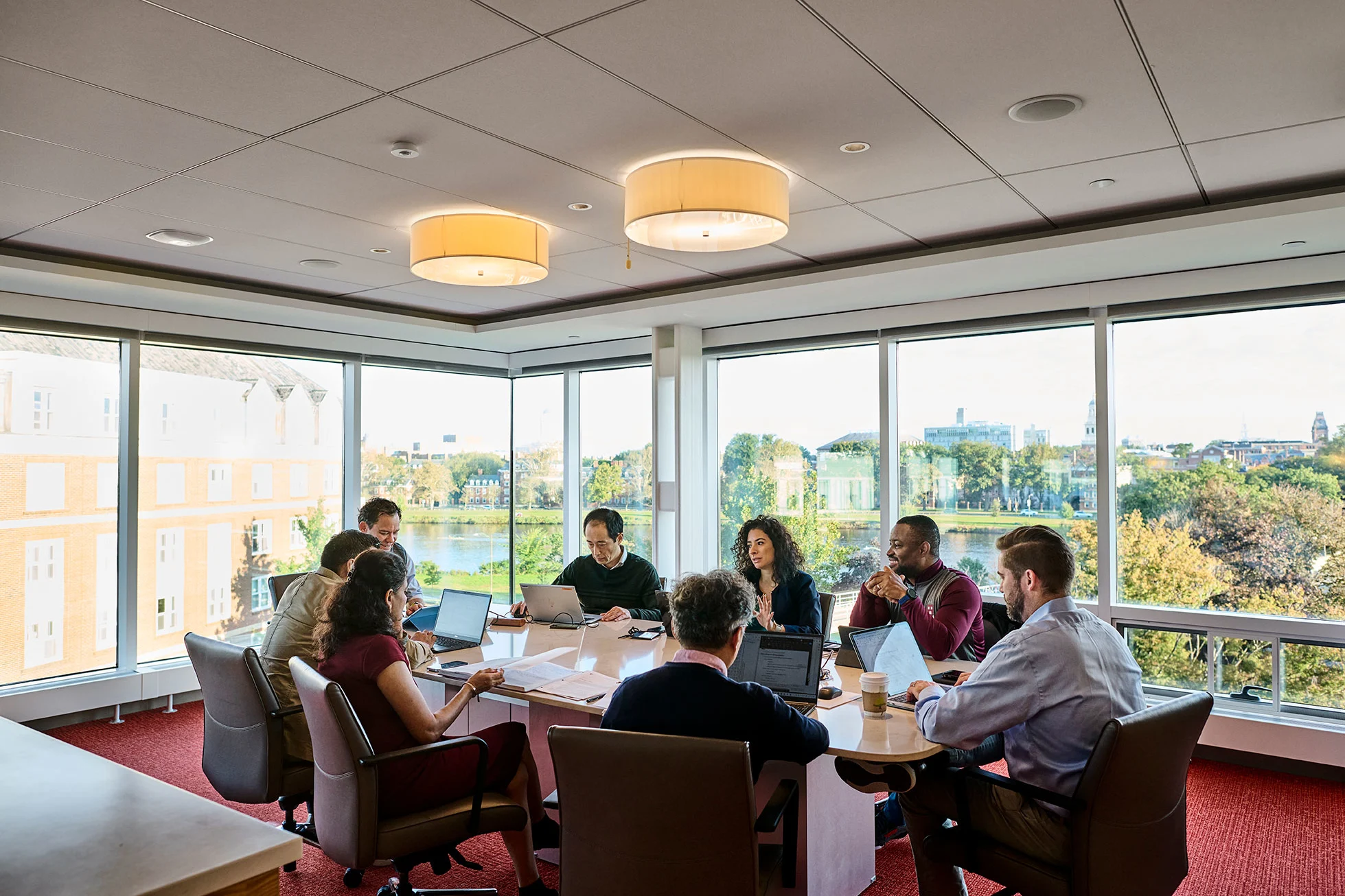 Executives sit around a table to discuss a business case inside Tata conference room overlooking campus