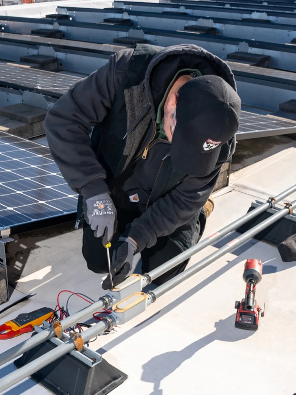 An Operations employee affixes solar panels to a roof on the Harvard Business School campus.