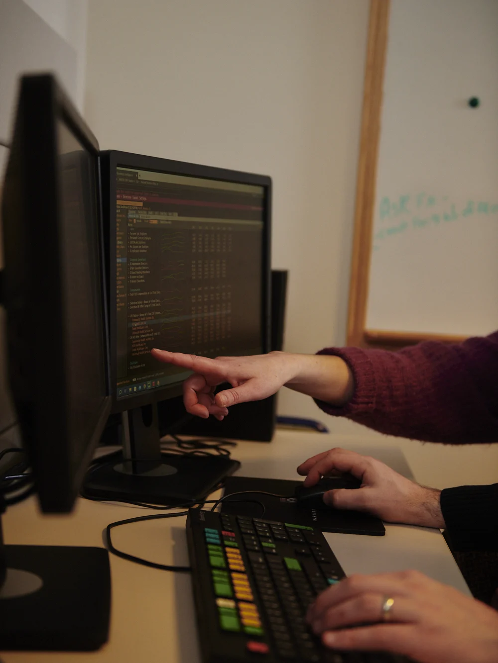 Close up of two individual's hands typing and gesturing at a Bloomberg terminal display and keyboard.