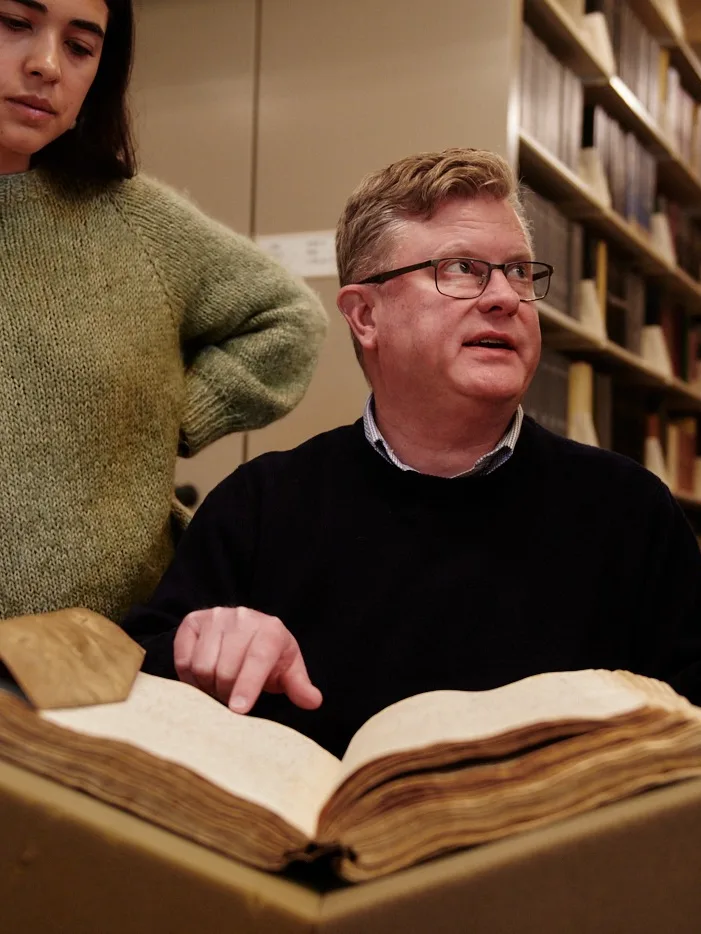 Man pointing to book bound in parchment