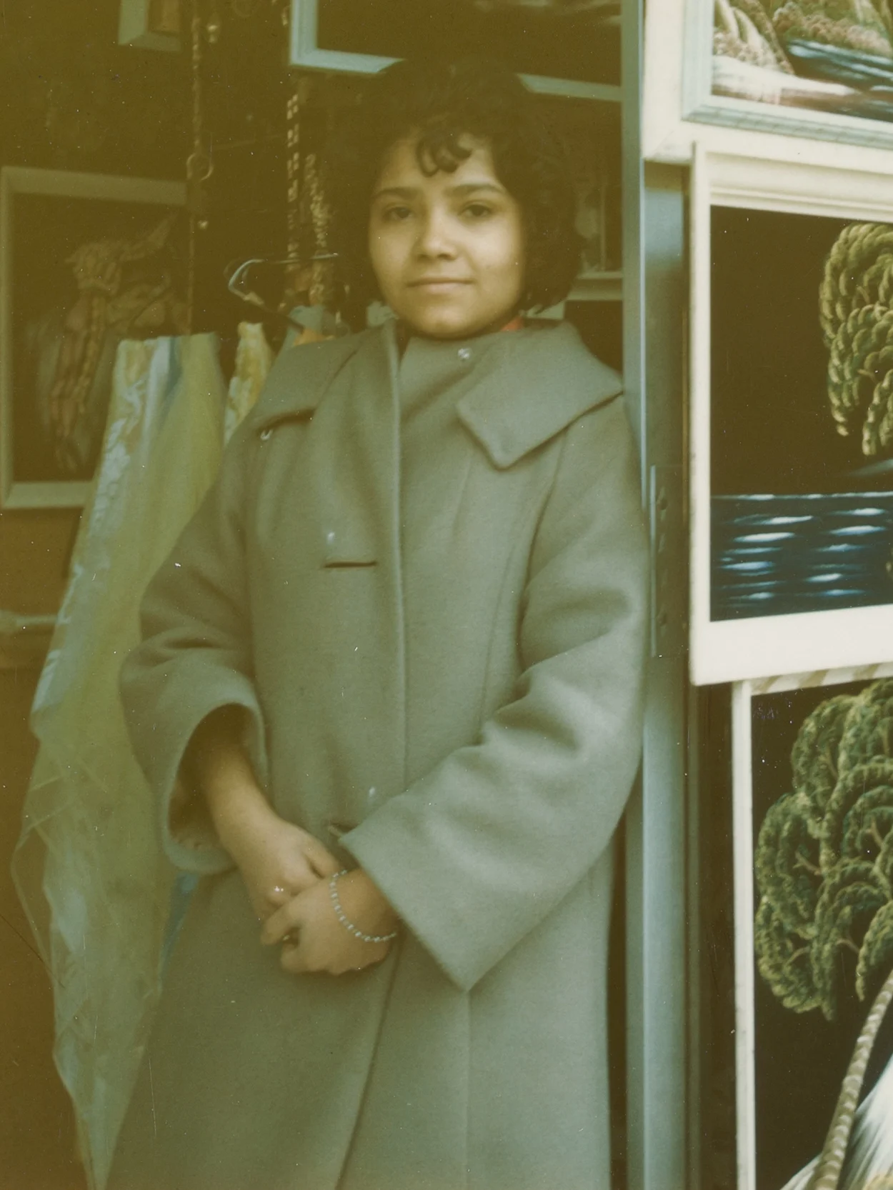 Woman in green coat leaning against art rack