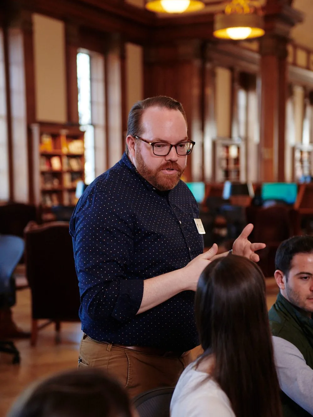 Staff member in Stamps Reading Room assisting seated students