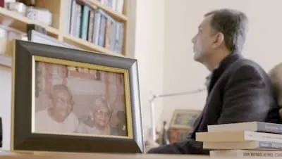 Professor Mihir Desai works in his office alongside a photograph of his parents