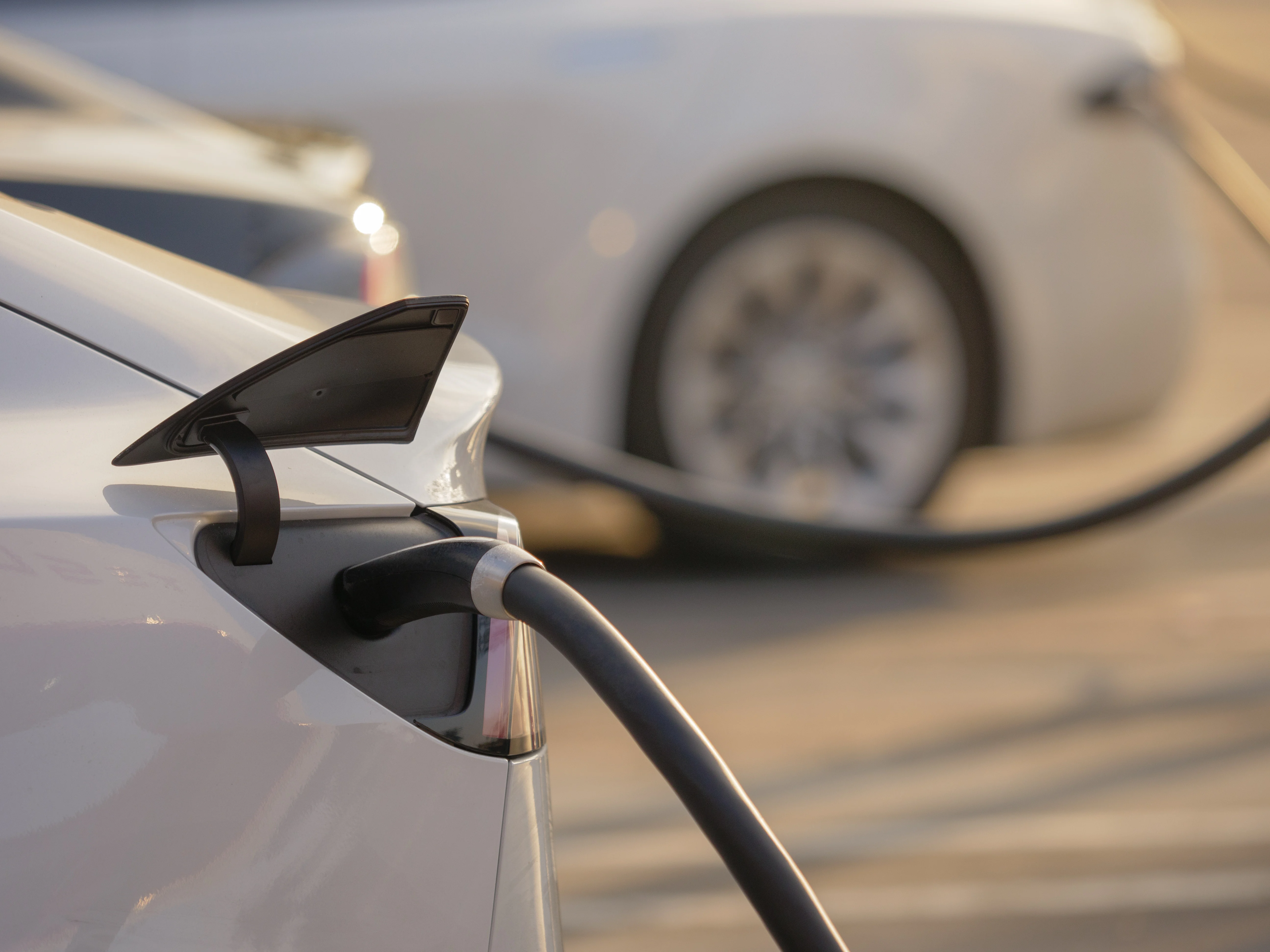 Electric cars charging at charging station outdoors at sunset.
