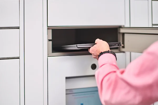 A person reaches to place a laptop inside a TSS locker