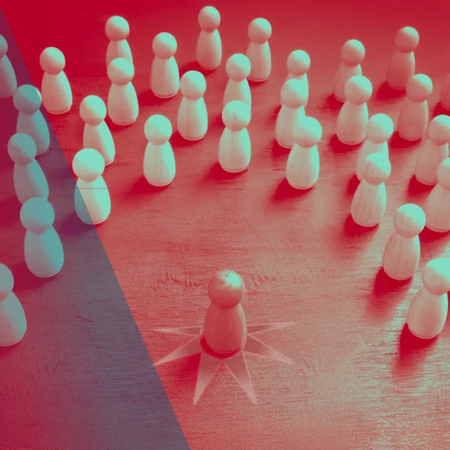 Light wooden pegs arranged in a semi-circle on a red surface; one piece with a starburst emanating from it stands in the center of the the clustered group.