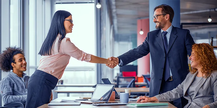 Business professionals shaking hands across a conference table during a successful negotiation meeting.