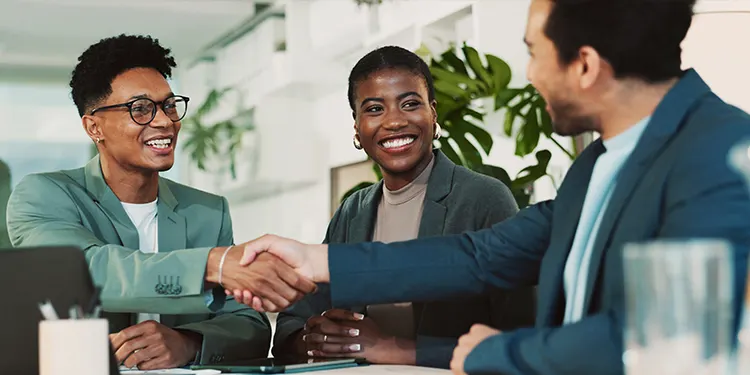 Business professionals shaking hands across a conference table.