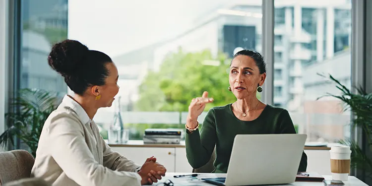 Two colleagues giving and receiving feedback during a one-on-one workplace conversation.