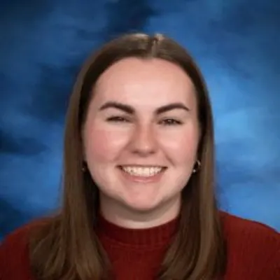 A woman with brown hair past her shoulders in a red shirt smiling.