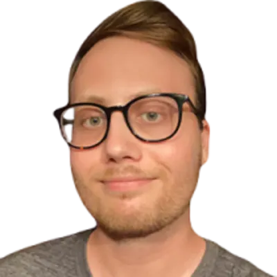 A man in glasses with quaffed hair and light stubble.