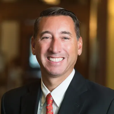 Ken Peterson in an in a black suit and red tie