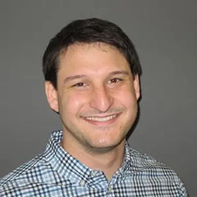 Daniel Mangoubi headshot in plaid shirt smiling