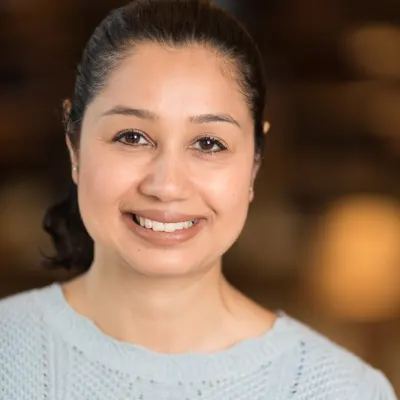 Farha Hasan headshot in purple smiling