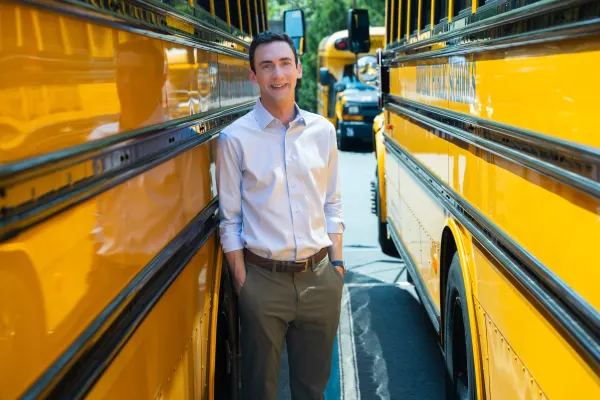 Ben Schutzman (MBA 2016) in front of electric school buses