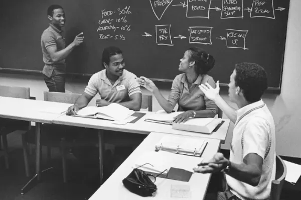 Students in a classroom. One working at a blackboard