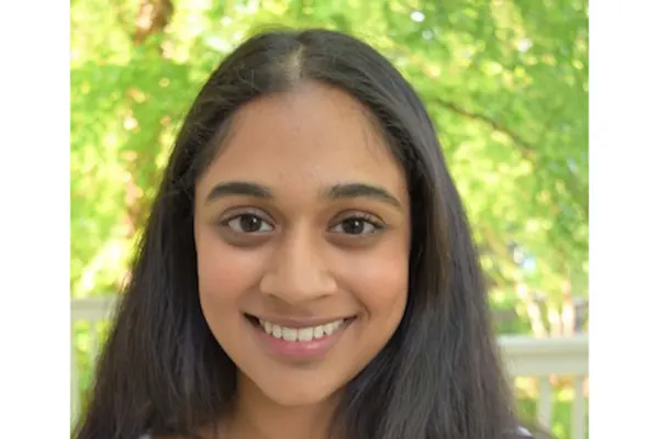 A young woman with long hair smiles warmly at the camera, exuding a cheerful and friendly demeanor.