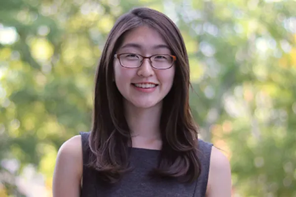 A young woman wearing glasses and a black top, looking confidently at the camera.