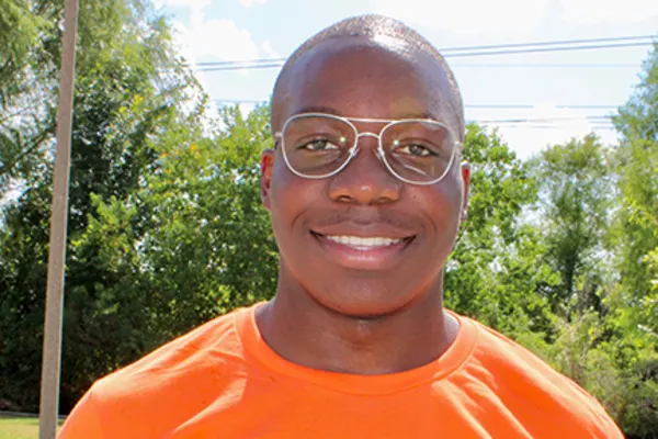 A man with glasses looking directly at the camera, wearing a casual shirt and smiling.