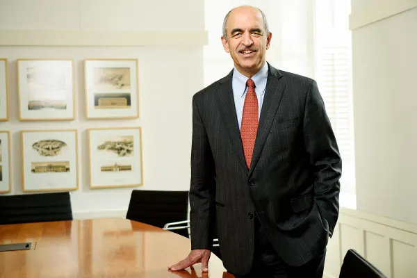 Dean Srikant Datar smiles while standing beside a conference table in his office.