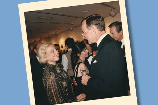 Muriel Siebert smiling and speaking with George H. W. Bush at a formal event with guests in evening attire.