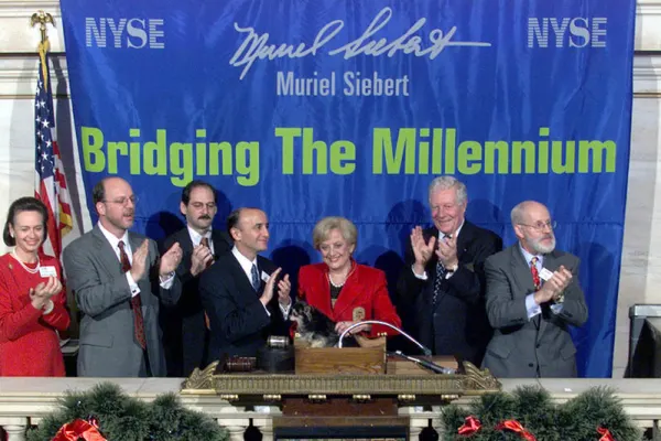 Muriel Siebert rings NYSE bell with a group under a banner reading “Bridging The Millennium.”