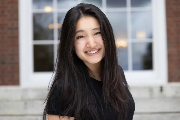 A young woman with long black hair smiles warmly at the camera.
