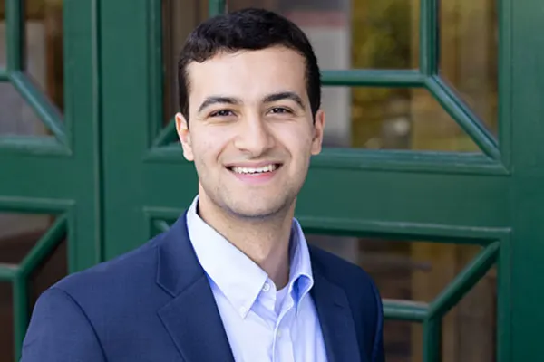 A man in a suit and tie stands confidently in front of a vibrant green door.