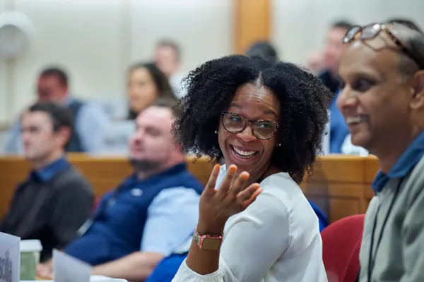 Woman in a classroom speaking to a classmate and smiling