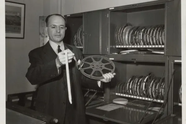 Man in suit reviewing reel of film
