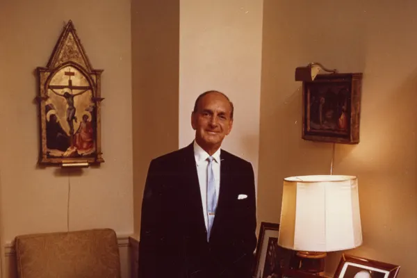 Man in suit standing next to framed pictures