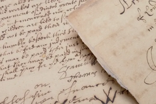Overlapping pieces of parchment with rough edges. They're covered in black writing presumably from a quill.